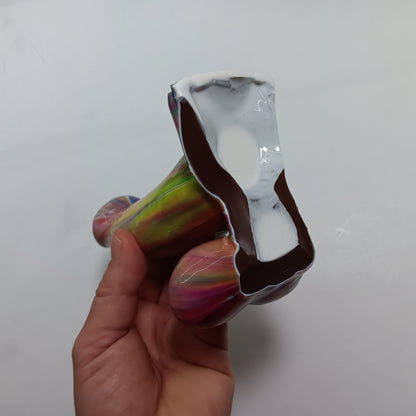 Detail view from the underside.  The toy is solid.  The underside is painted white in the center with brown silicone trimmed around the outside.  The underside is mostly white with some brown.