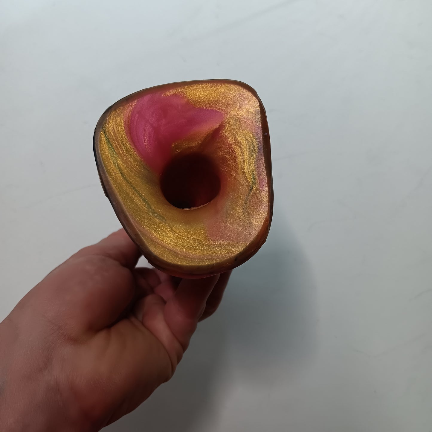 Bottom view of the Pink and Gold B.J. dildo showing a concurved underside of the base with a hole in the center to provide suction forcthe wearer.