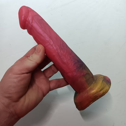 Right side of pink, gold, dark blue B.J. dildo. Mostly hot pink with pearly swirls.